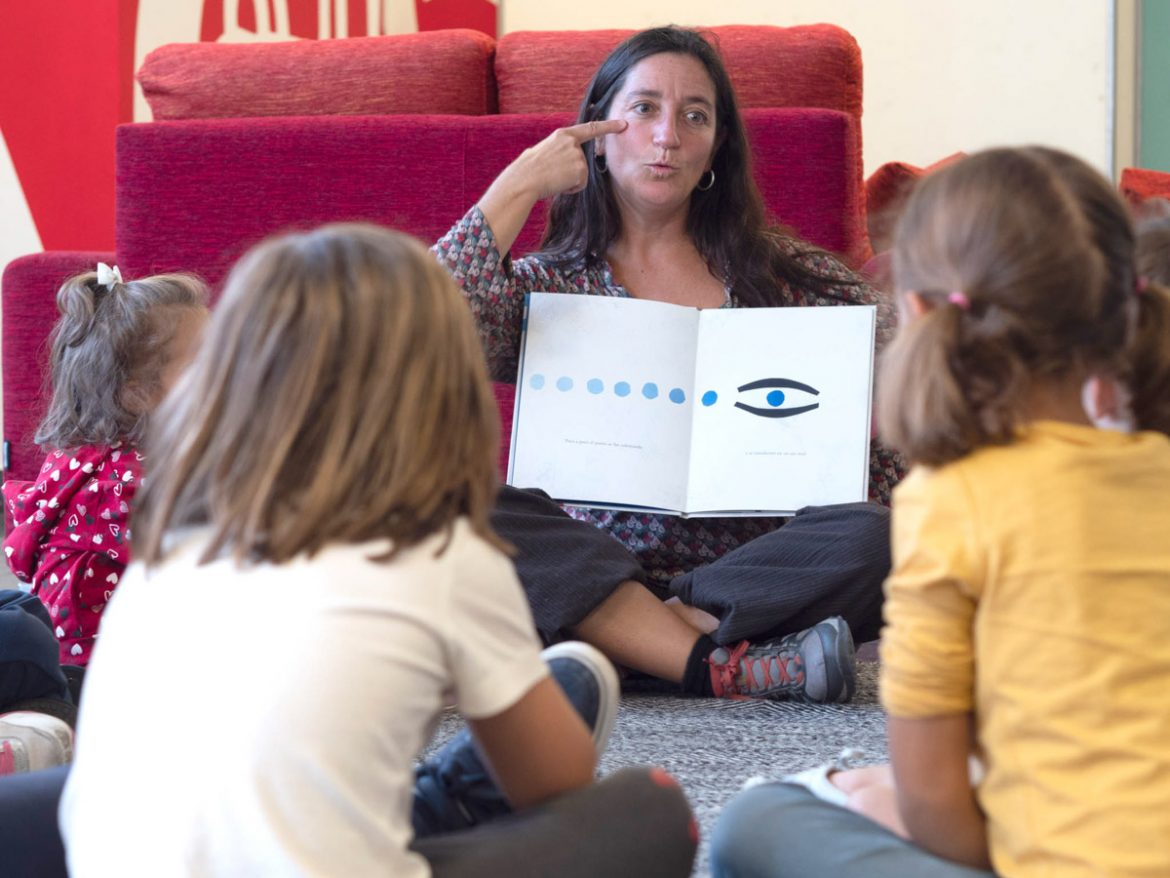 Mujer cuenta un cuento a un grupo de niños