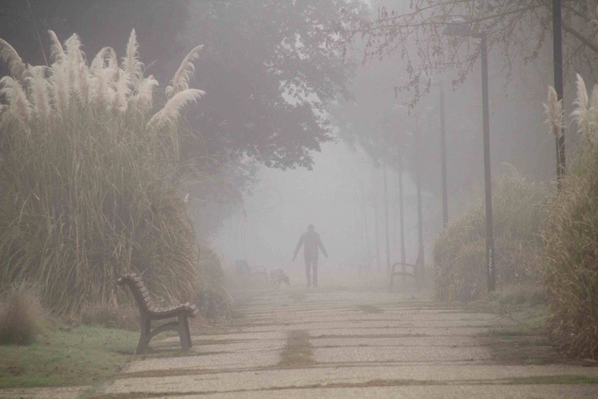 Un hombre paseando a su perro por la ribera del río. ENA